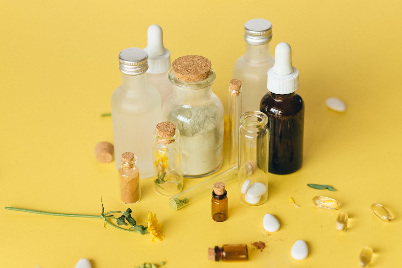 Assorted bottles and herbs showcasing natural medicine on a vibrant yellow surface.